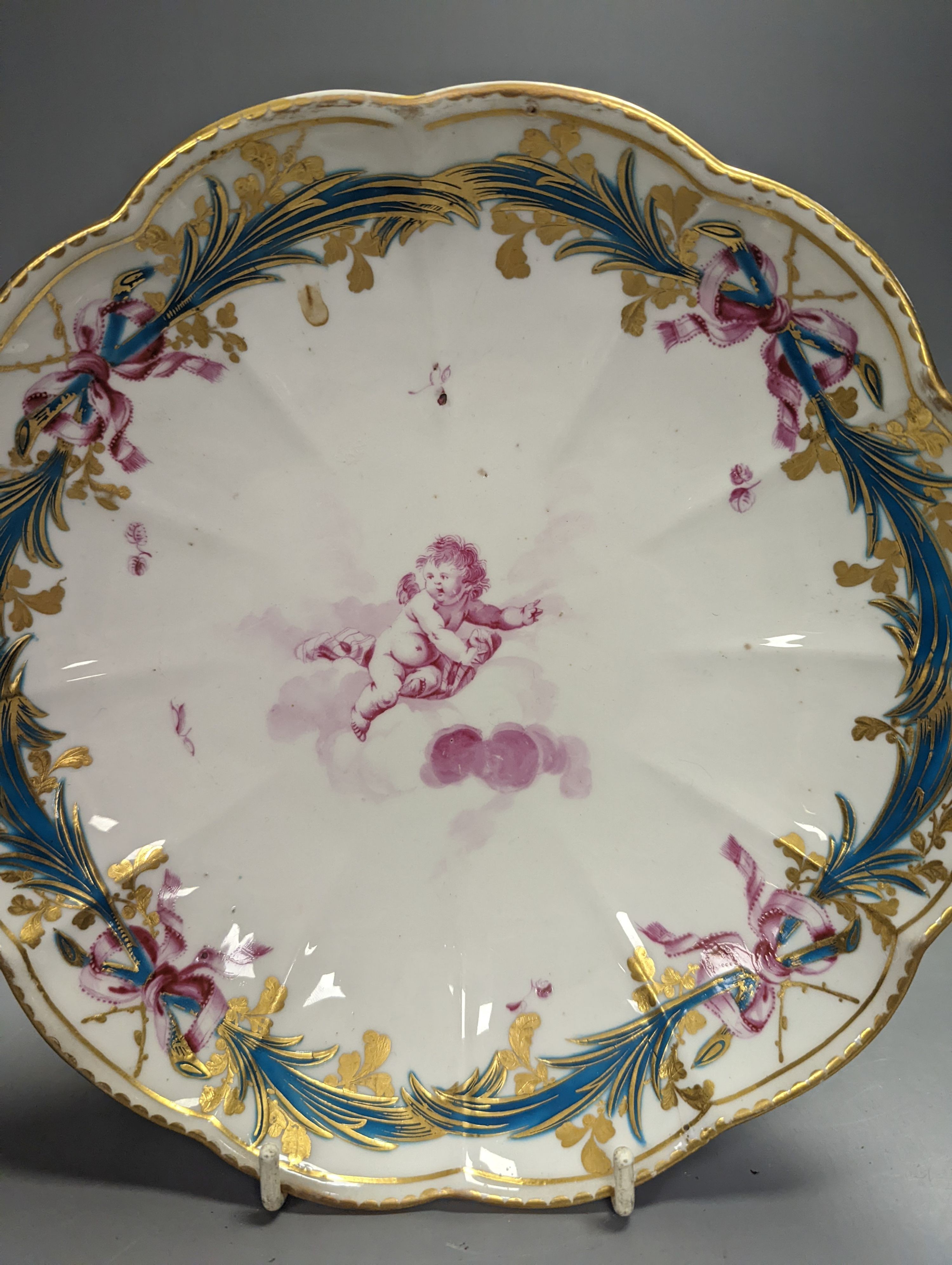 A Chelsea-Derby circular dish painted in puce with a cherub floating on a cloud by Richard Askew, c.1775, 22cm